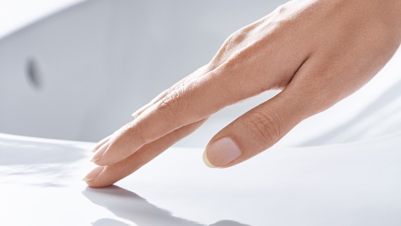 Hand streicht über Waschtischkeramik mit Spezialglasur KeraTect® Hand streicht über Waschtischkeramik mit Spezialglasur KeraTect®