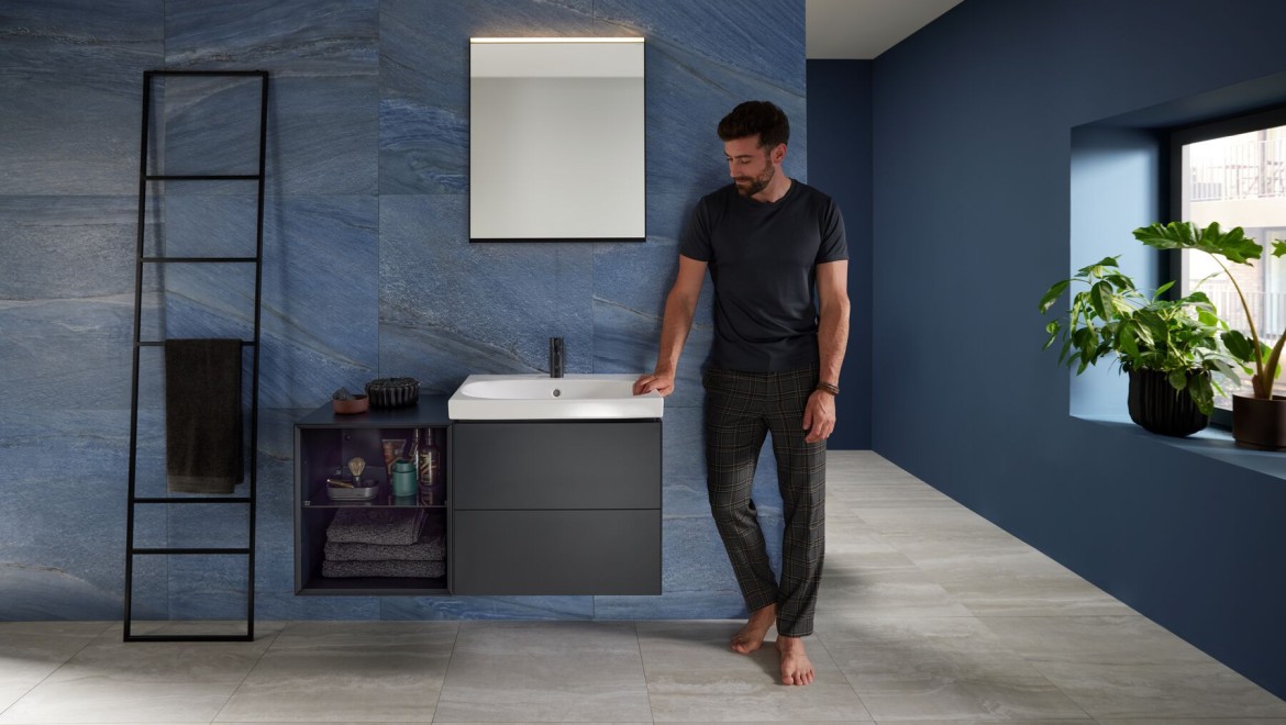 Mann neben seinem Waschplatz ausgestattet mit Produkten der Geberit Serie ONE, Acanto und Option Lichtspiegel Mann neben seinem Waschplatz ausgestattet mit Produkten der Geberit Serie ONE, Acanto und Option Lichtspiegel