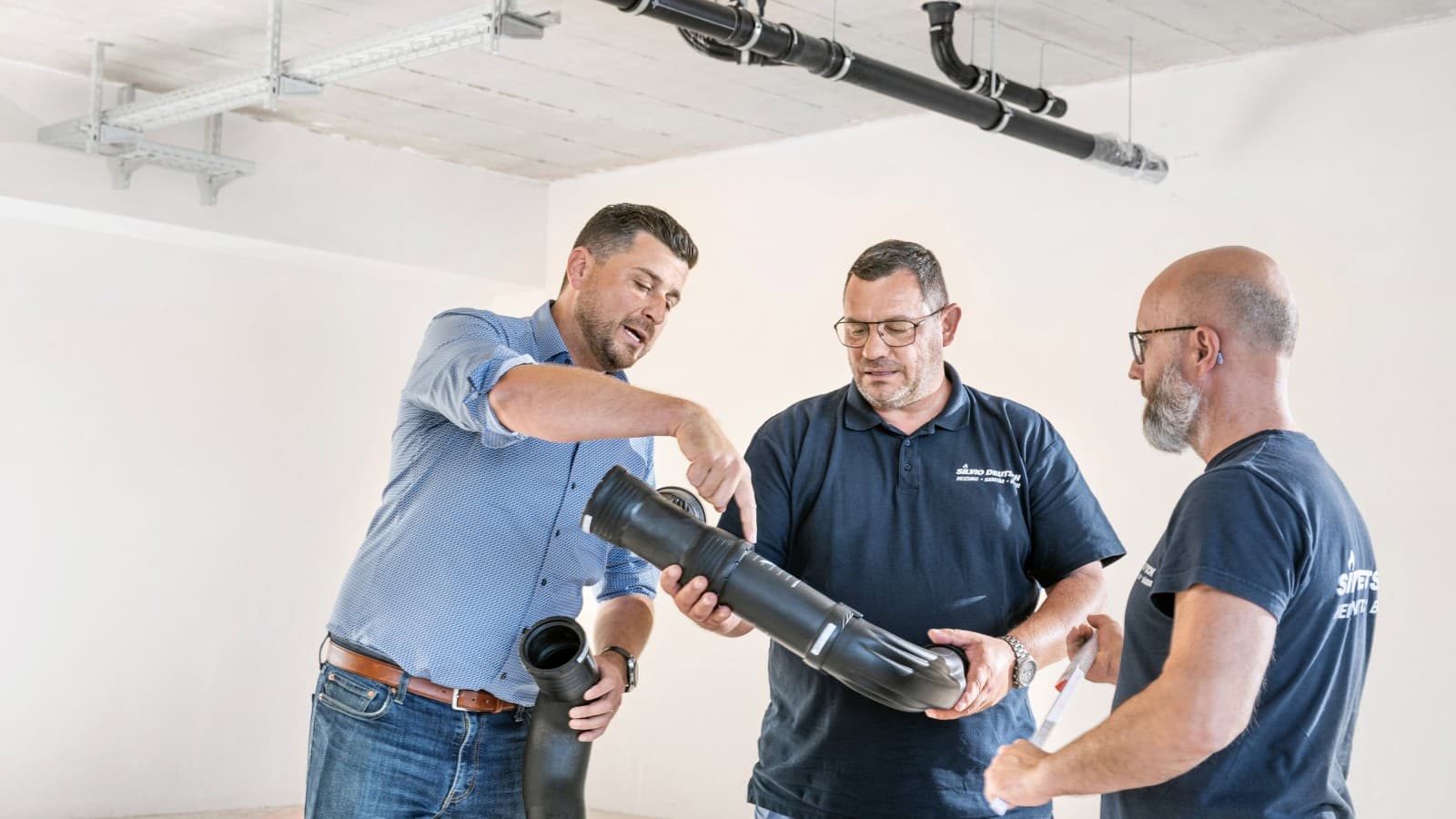 Geberit Verkaufsberater Fabian Ritter erklärt Projektleiter Marcel Roth und seinem Team den neuen Geberit Silent-Pro BottomTurn Bogen Geberit Verkaufsberater Fabian Ritter erklärt Projektleiter Marcel Roth und seinem Team den neuen Geberit Silent-Pro BottomTurn Bogen